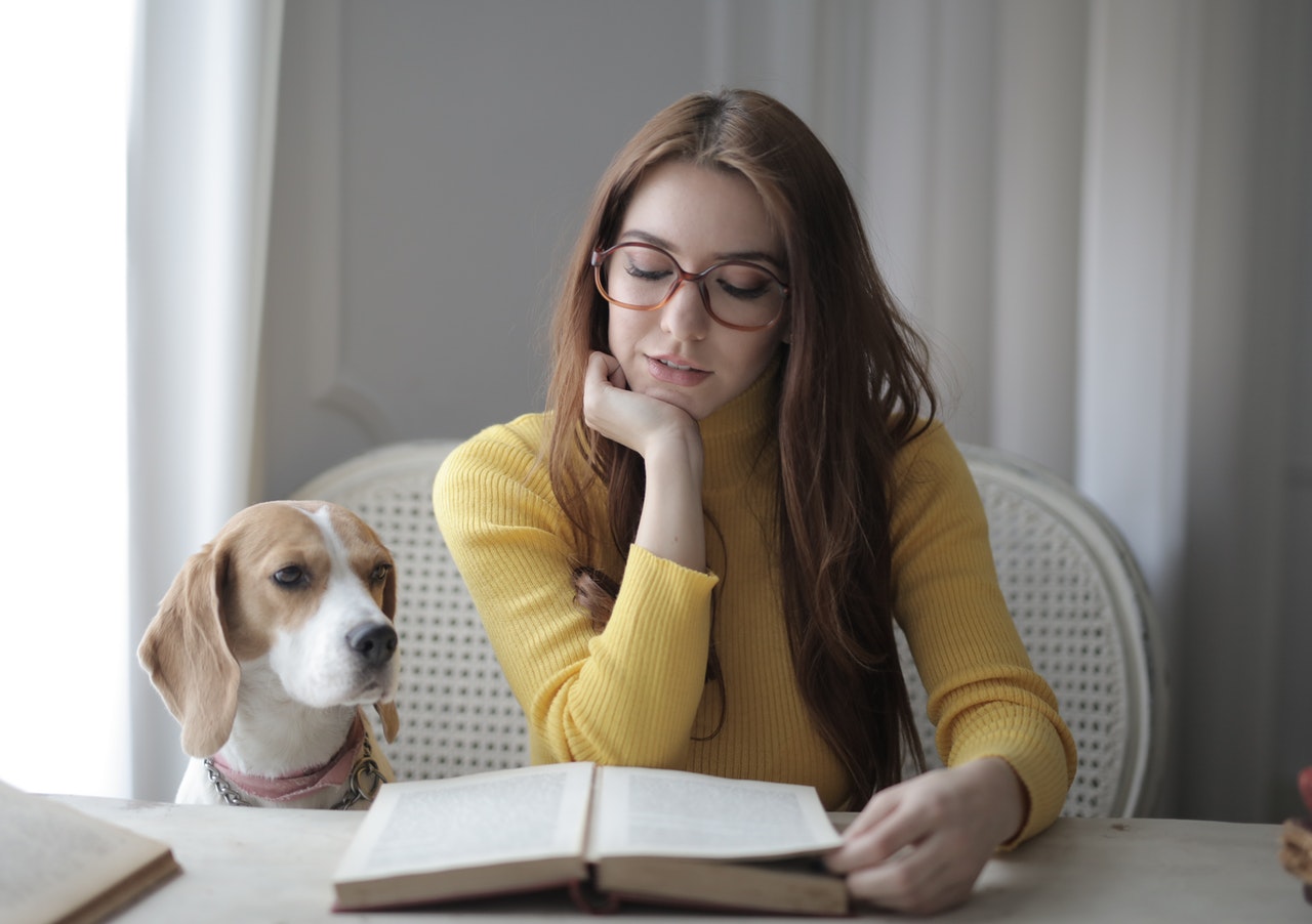 a dog next to a reading woman